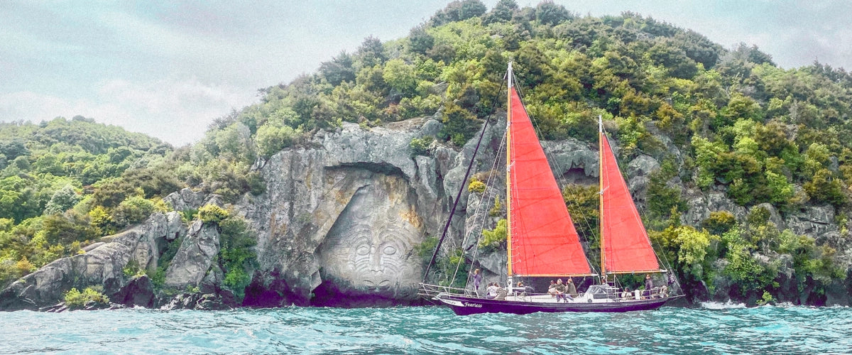 A red sailboat in front of a Maori carving at Lake Taupo