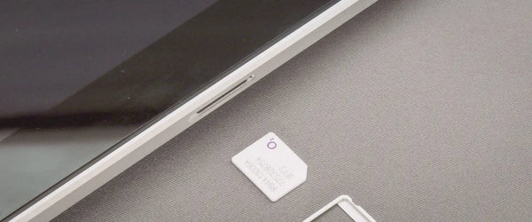 A physical SIM next to a smartphone