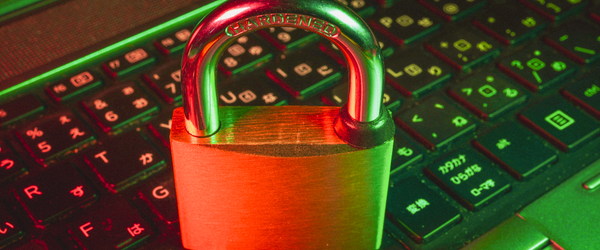 A padlock resting on top of a laptop keyboard, in red-green neon lighting