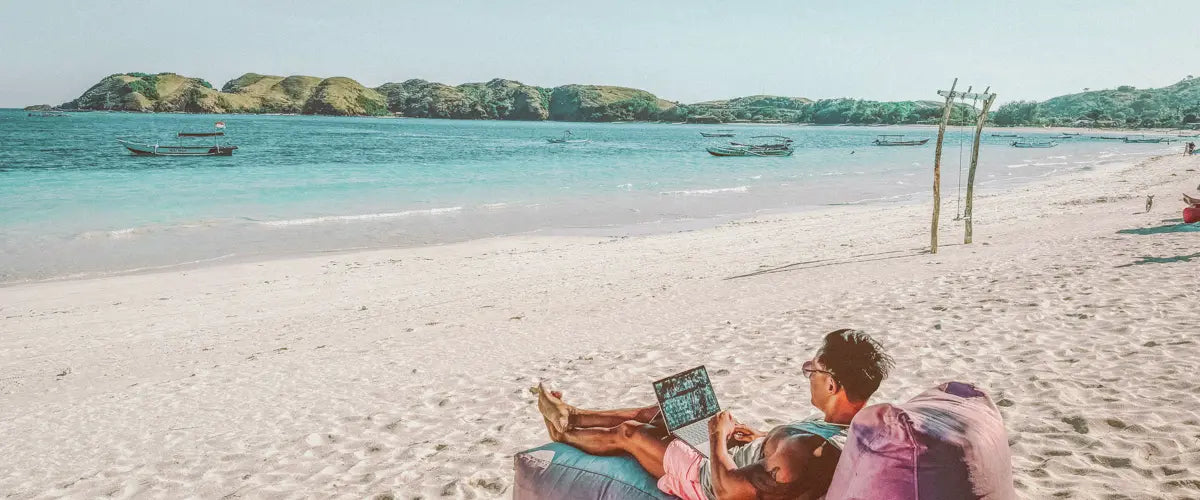 Someone using a laptop while relaxing on the beach