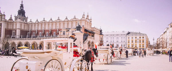 Horse-drawn carriages lining up on the cobblestones of the Main Market Square, Rynek Główny, in Kraków, Poland.