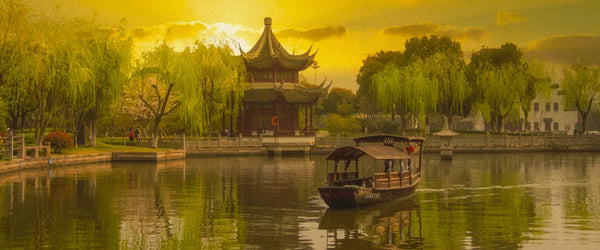 The sun going down over a brown house, a boat, and trees in Shanghai, China
