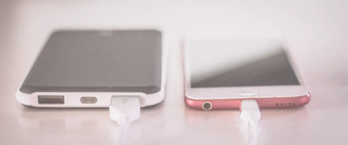 Two smartphones plugged in to charge up on a table