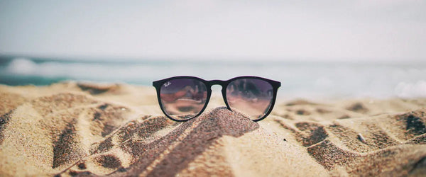 A pair of sunglasses resting on a sandy beach