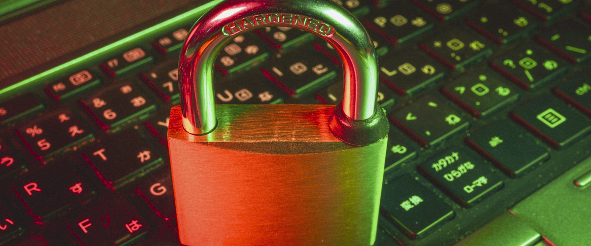 A padlock resting on top of a laptop keyboard, in red-green neon lighting