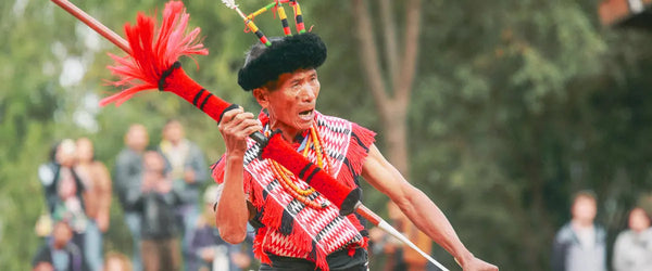 A man in traditional dress, wielding a sword, taking part in the Nagaland Hornbill Festival in India