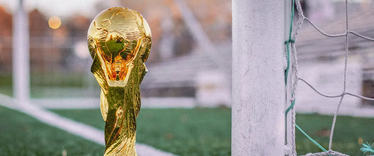 The FIFA World Cup trophy next to soccer goalposts